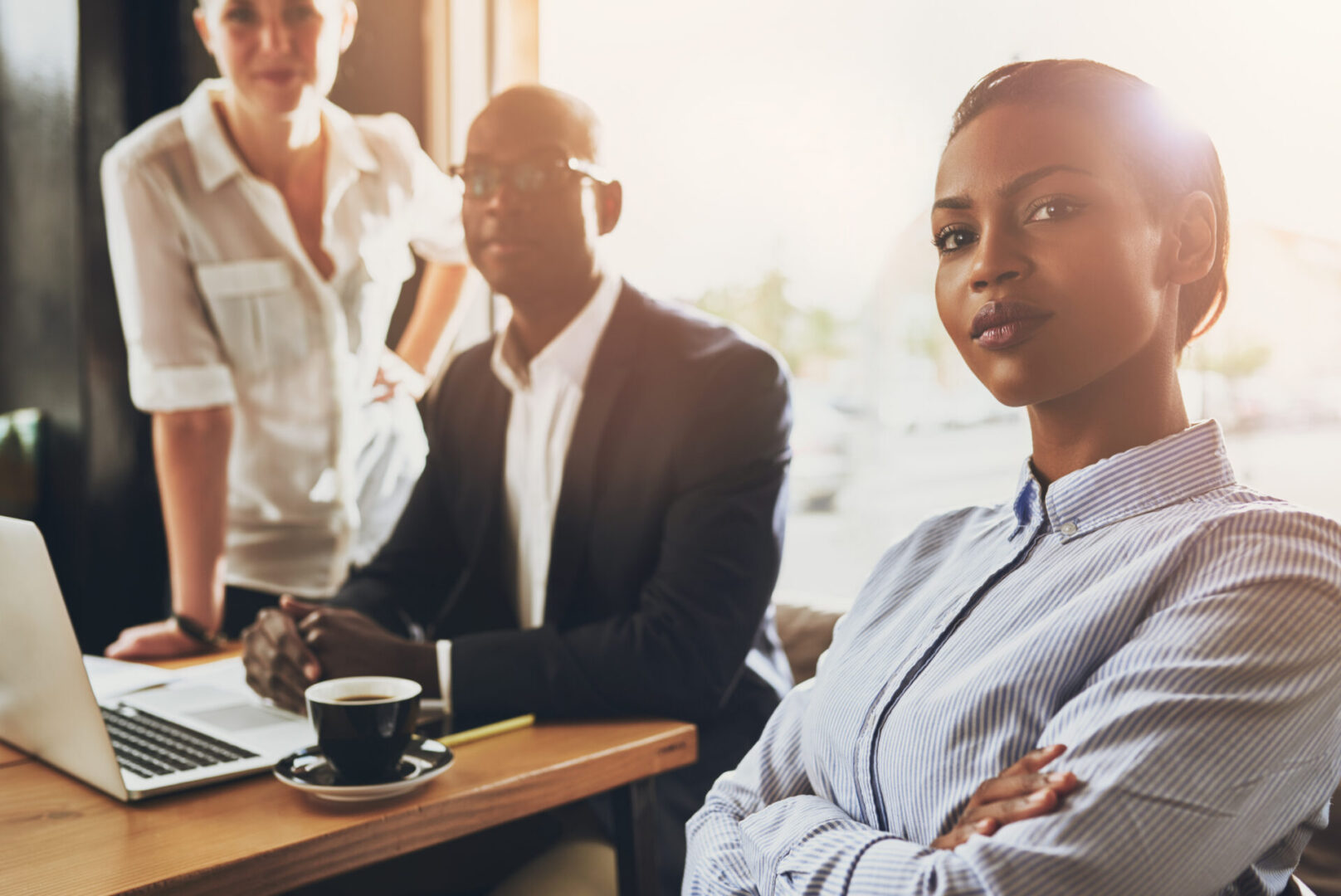 Confident young black business woman sitting in front of other business people